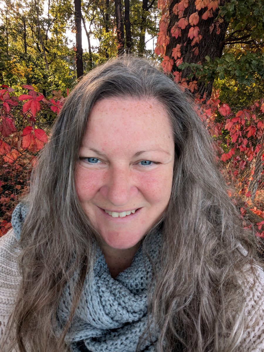 Aline Förster, lächelnd vor Herbstlaub